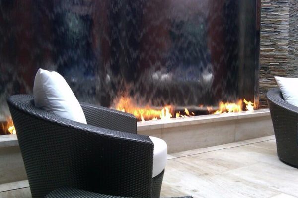 propane fire pit next to waterfall wall